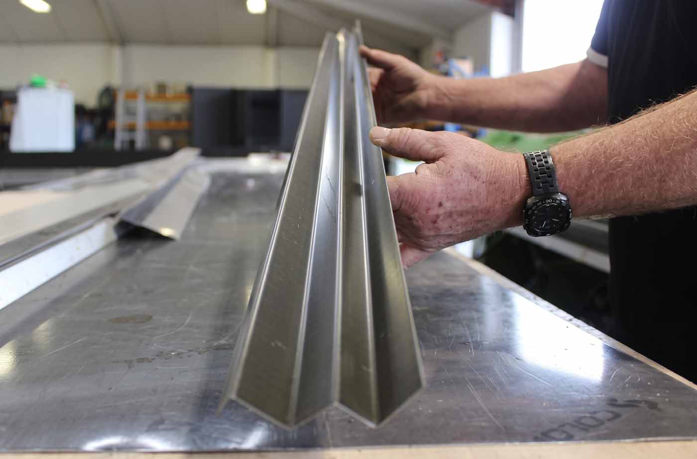 Checking a fold on a custom flashing in the workshop before fitting